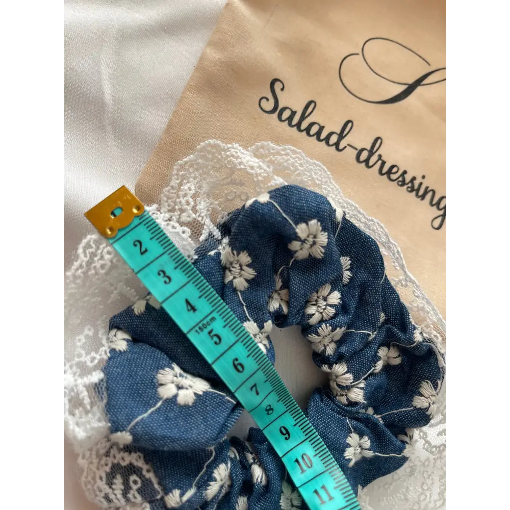 Chouchou denim brodé avec fleurs et détails en dentelles pour une coiffure tendance et raffinée.