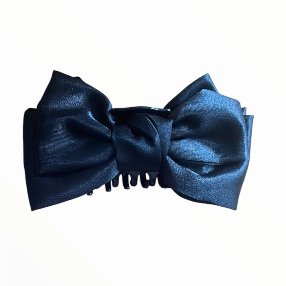 Détail de la pince à crabe noire avec son nœud papillon en satin, parfait pour maintenir les cheveux avec raffinement.